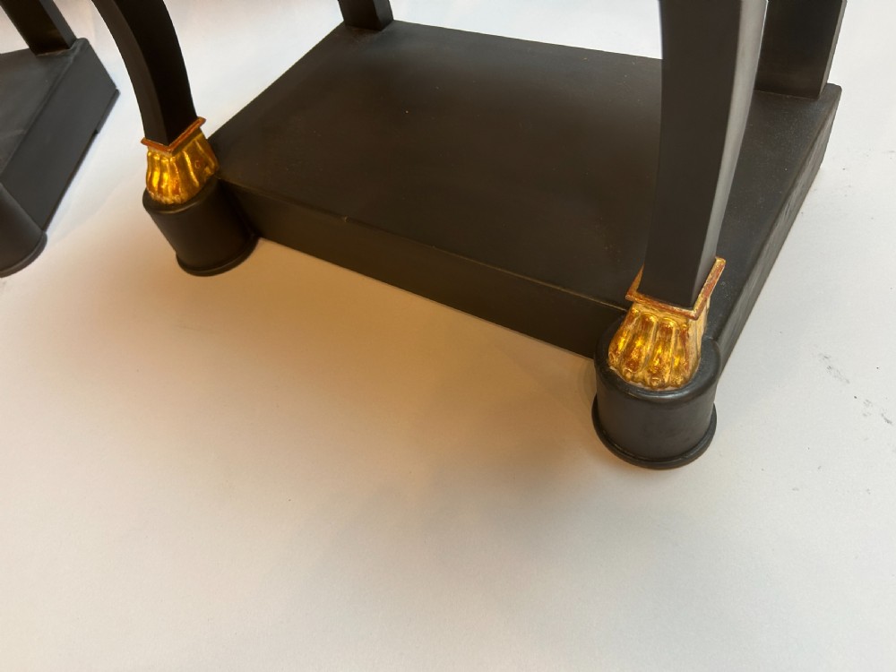 A pair of ebonised black French Empire style bedside chests featuring grey marble tops, three small drawers with ring pulls, curved front legs with gilt paw feet, and an undertier shelf. View IV