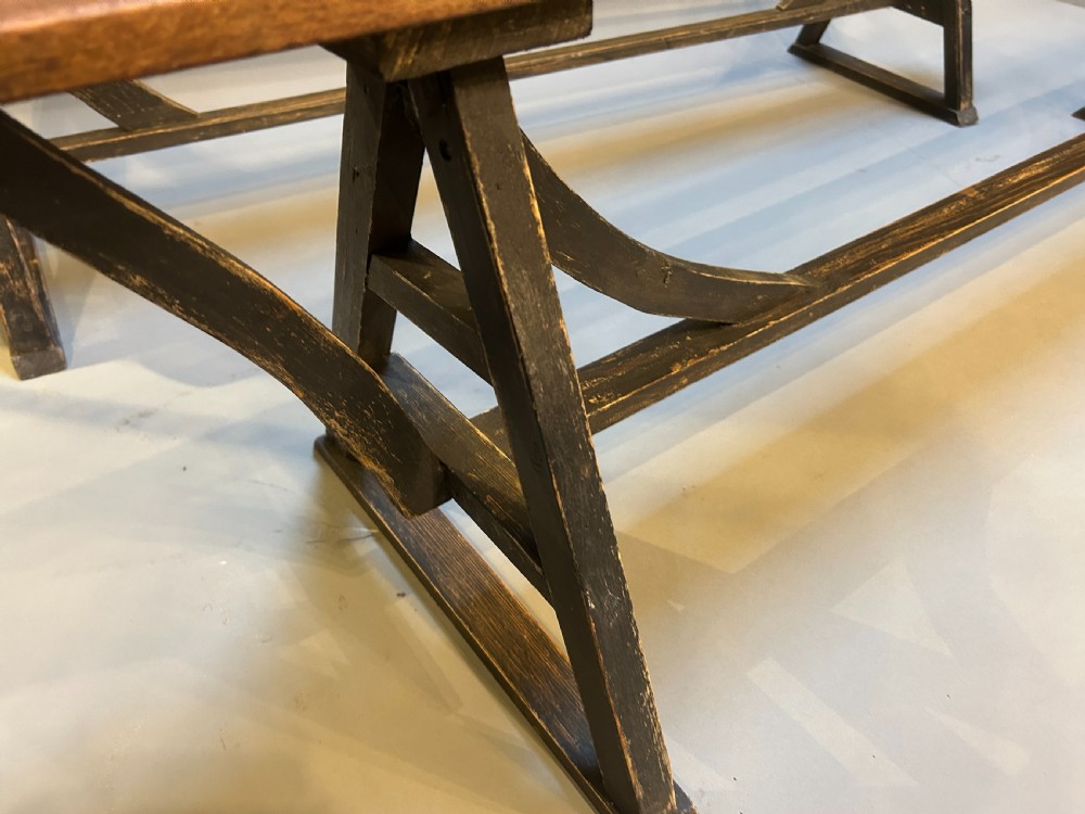 A pair of long wooden benches featuring warm brown timber plank tops supported by black painted trestle bases. View IV