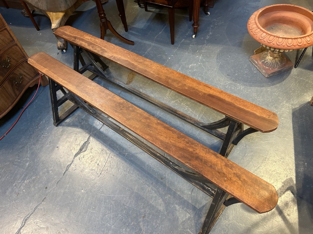 A pair of long wooden benches featuring warm brown timber plank tops supported by black painted trestle bases. View VIII