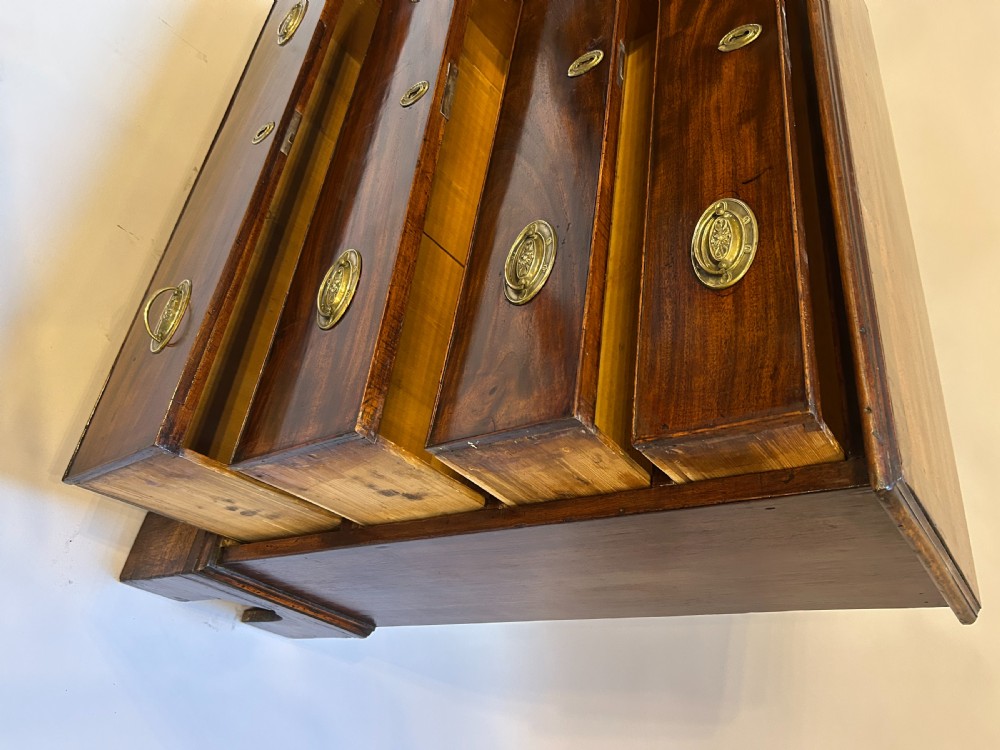 A George III dark mahogany hall chest of drawers with four graduated drawers, oval brass handles, and bracket feet. View III