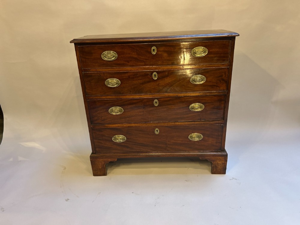 A George III dark mahogany hall chest of drawers with four graduated drawers, oval brass handles, and bracket feet. View V