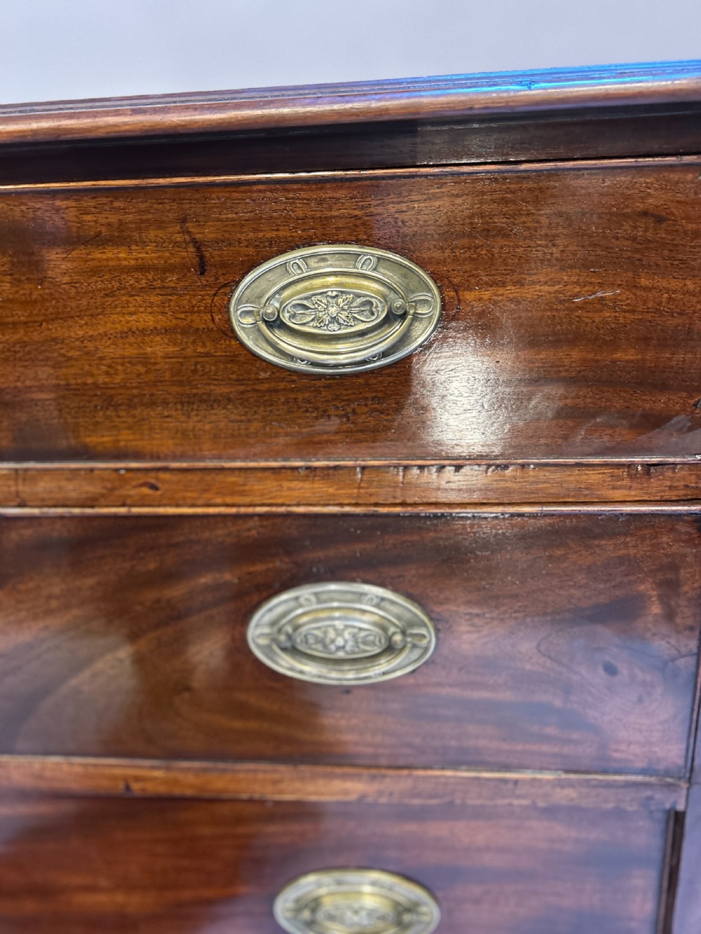 A George III dark mahogany hall chest of drawers with four graduated drawers, oval brass handles, and bracket feet. View VI