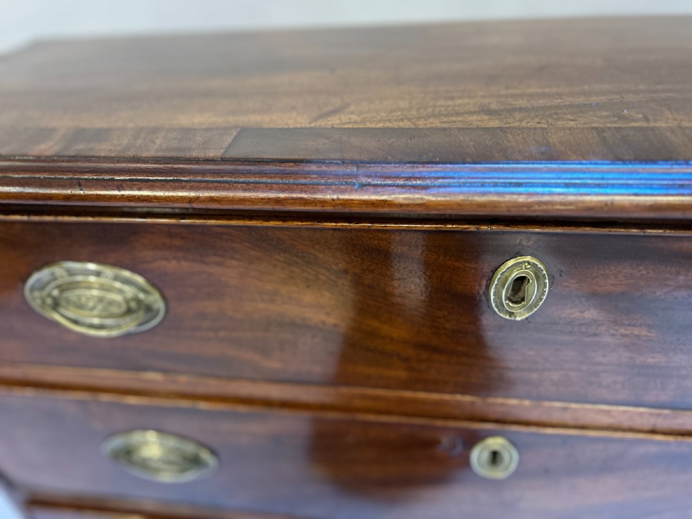 A George III dark mahogany hall chest of drawers with four graduated drawers, oval brass handles, and bracket feet. View VII