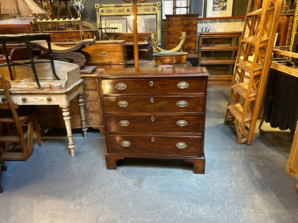 A George III dark mahogany hall chest of drawers with four graduated drawers, oval brass handles, and bracket feet. View VIII