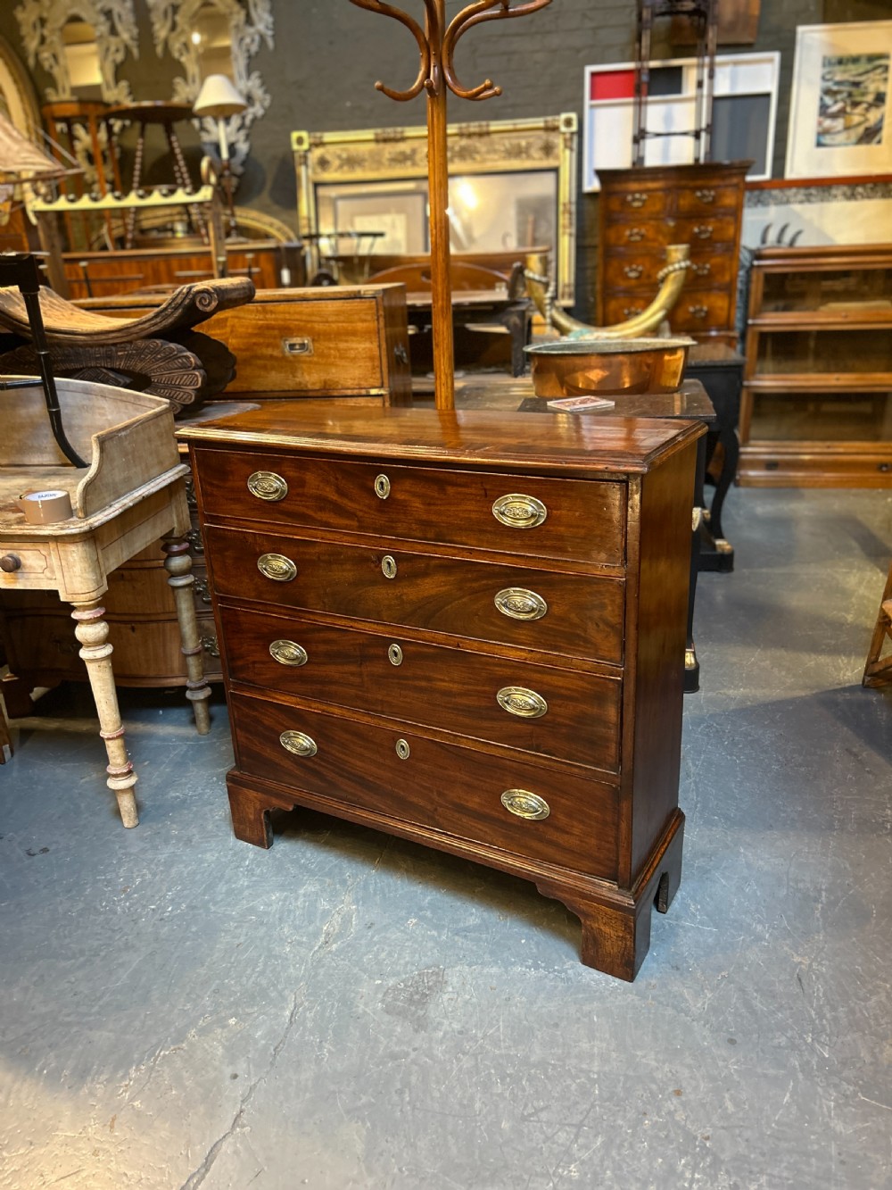 A George III dark mahogany hall chest of drawers with four graduated drawers, oval brass handles, and bracket feet. View XII