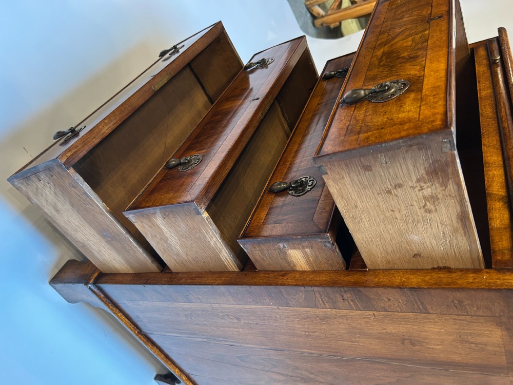 A Georgian Revival walnut bachelors chest featuring four drawers with brass drop handles, a brushing slide, and bracket feet. View III