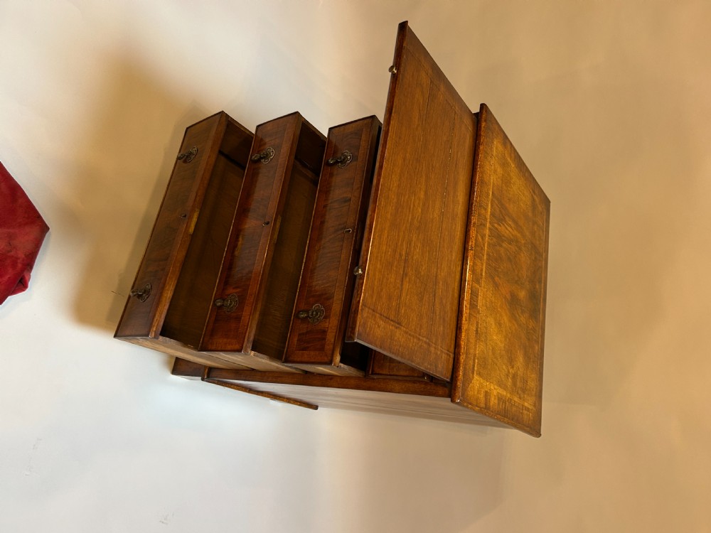 A Georgian Revival walnut bachelors chest featuring four drawers with brass drop handles, a brushing slide, and bracket feet. View IV