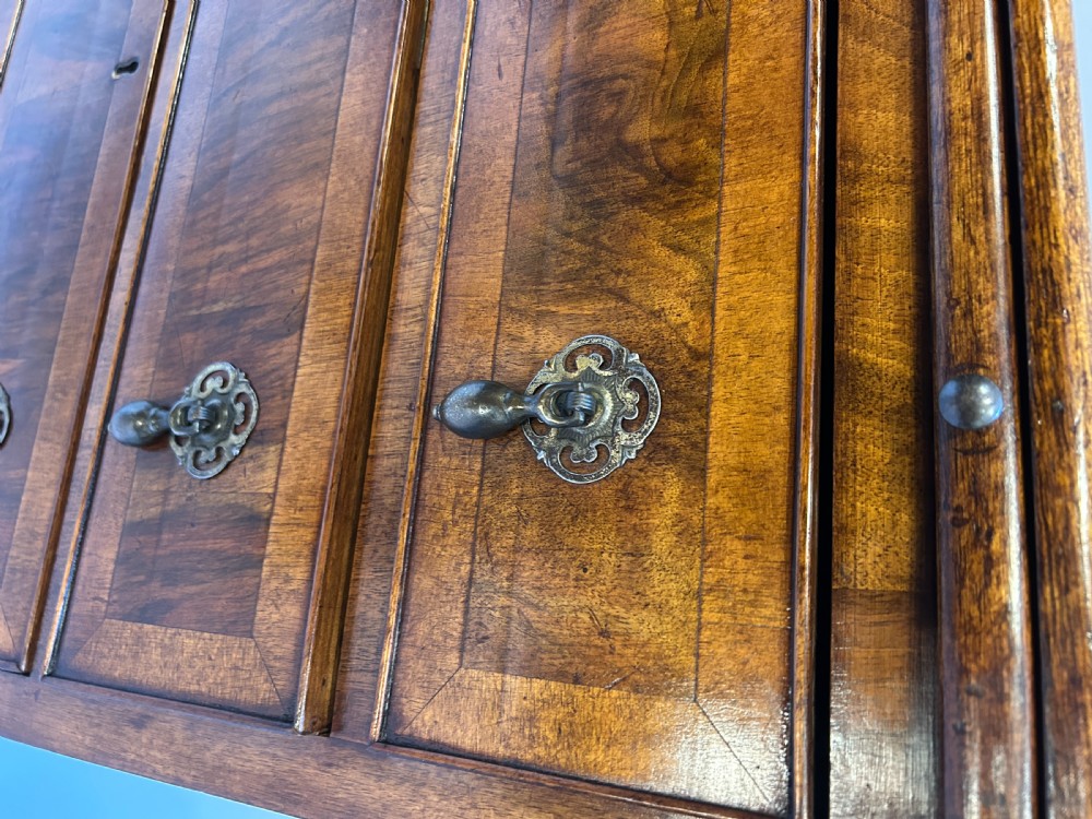 A Georgian Revival walnut bachelors chest featuring four drawers with brass drop handles, a brushing slide, and bracket feet. View VI