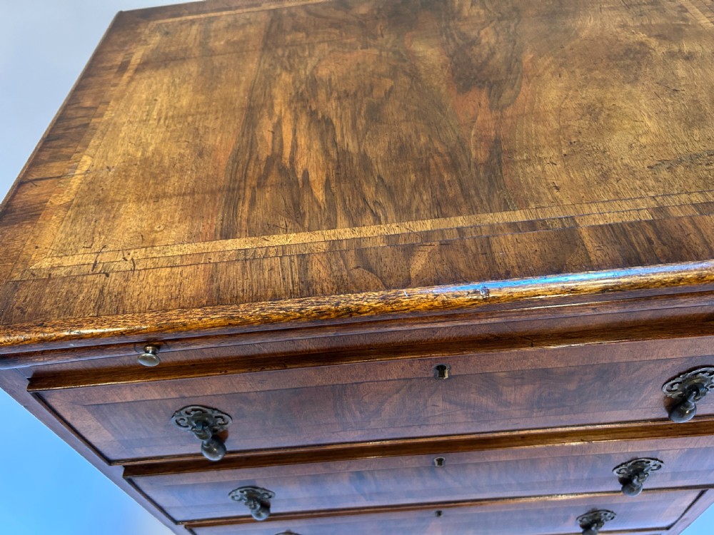 A Georgian Revival walnut bachelors chest featuring four drawers with brass drop handles, a brushing slide, and bracket feet. View VII
