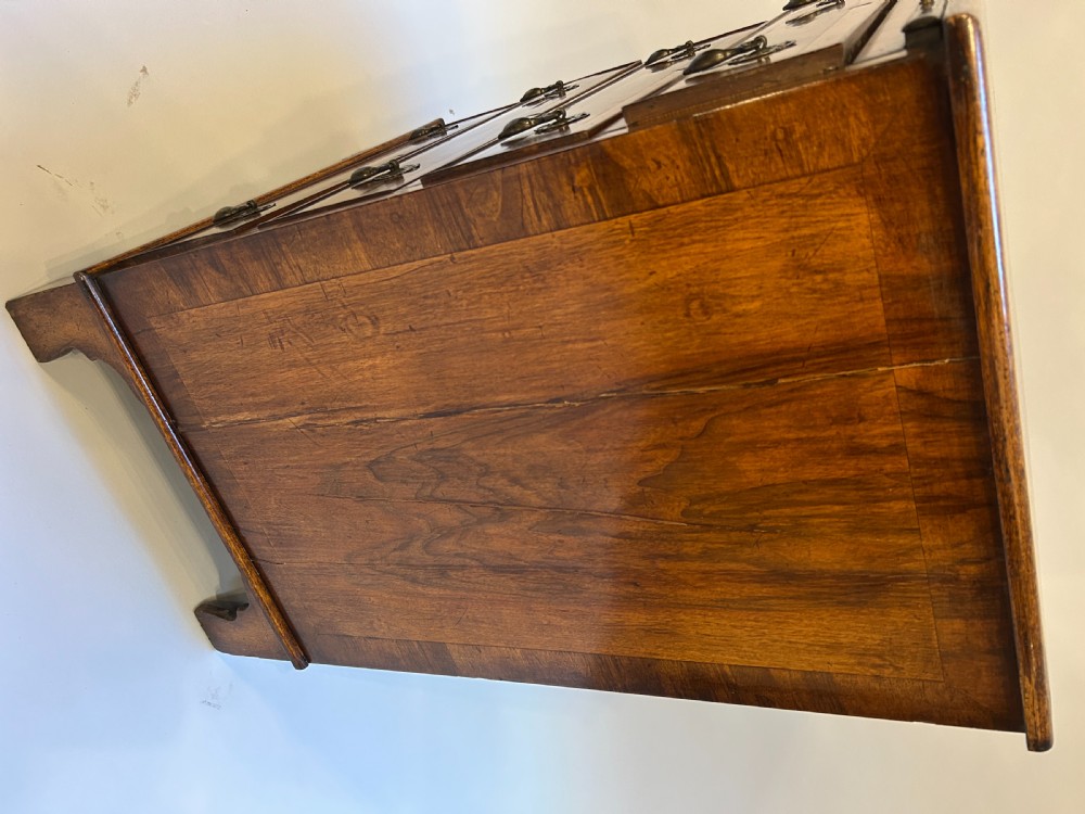 A Georgian Revival walnut bachelors chest featuring four drawers with brass drop handles, a brushing slide, and bracket feet. View VIII