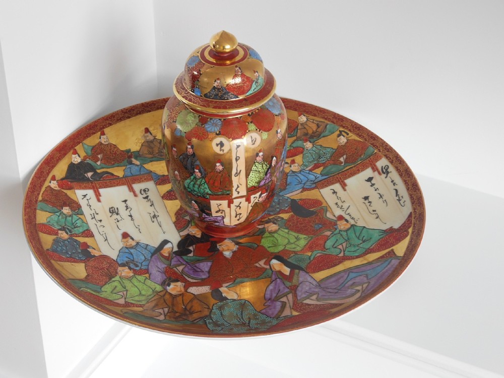 A Japanese Kutani porcelain charger plate and matching lidded vase decorated with hand-painted figures, calligraphy panels, and gold accents.