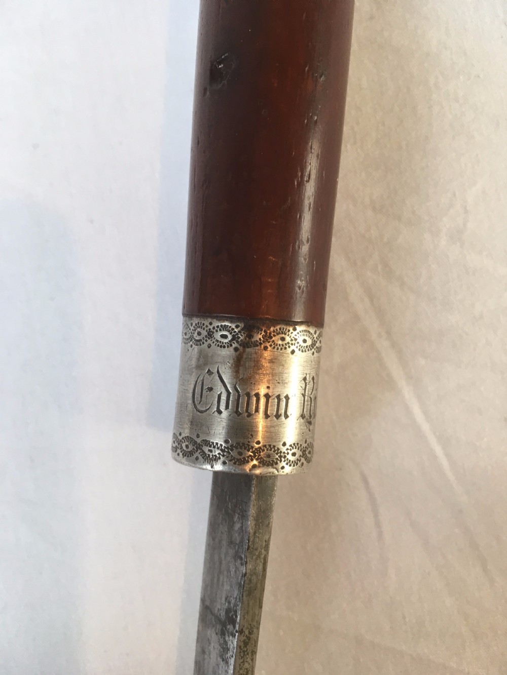 A Victorian hardwood sword stick separated to display a long steel blade beside its dark wooden sheath with a silver collar. View V
