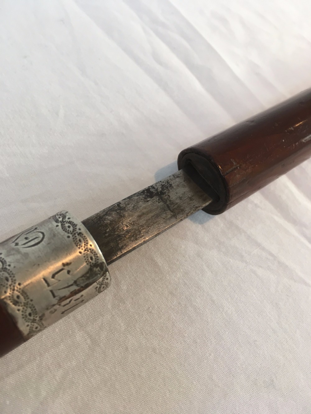 A Victorian hardwood sword stick separated to display a long steel blade beside its dark wooden sheath with a silver collar. View VIII