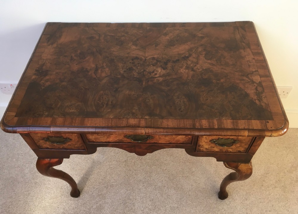 An eighteenth-century George II burr walnut lowboy featuring three drawers, brass handles, a shaped apron, and four slender cabriole legs. View III