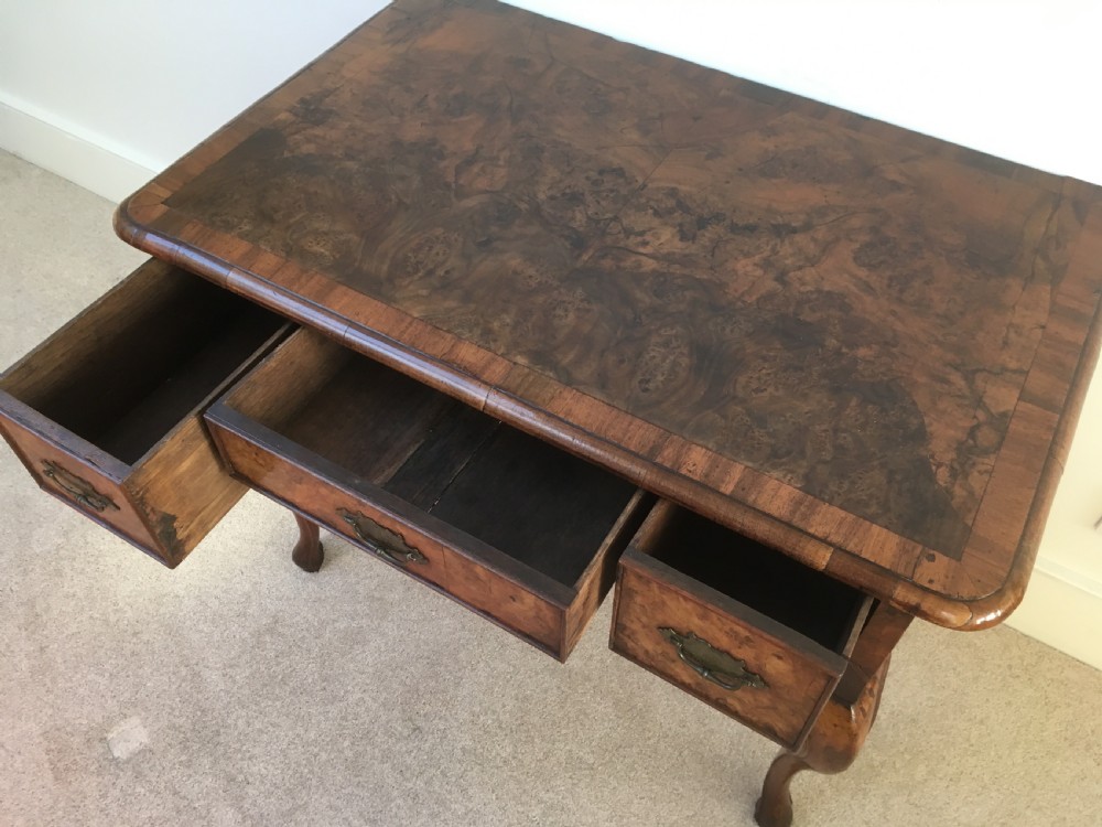An eighteenth-century George II burr walnut lowboy featuring three drawers, brass handles, a shaped apron, and four slender cabriole legs. View V