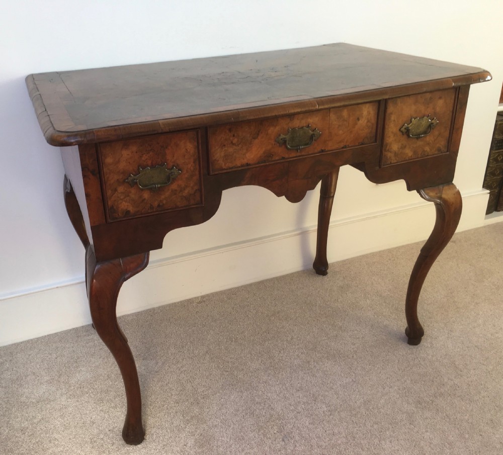An eighteenth-century George II burr walnut lowboy featuring three drawers, brass handles, a shaped apron, and four slender cabriole legs. View VII