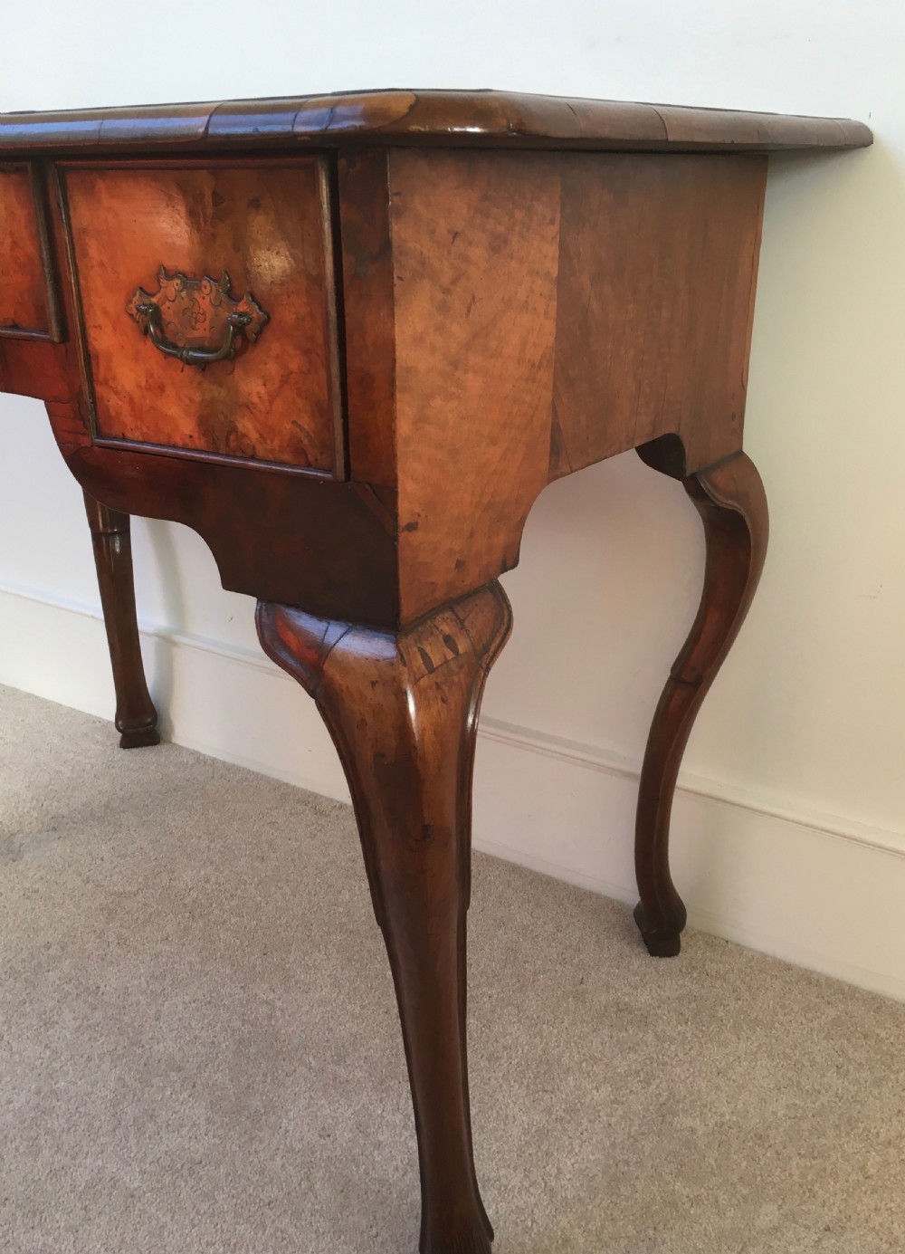 An eighteenth-century George II burr walnut lowboy featuring three drawers, brass handles, a shaped apron, and four slender cabriole legs. View IX