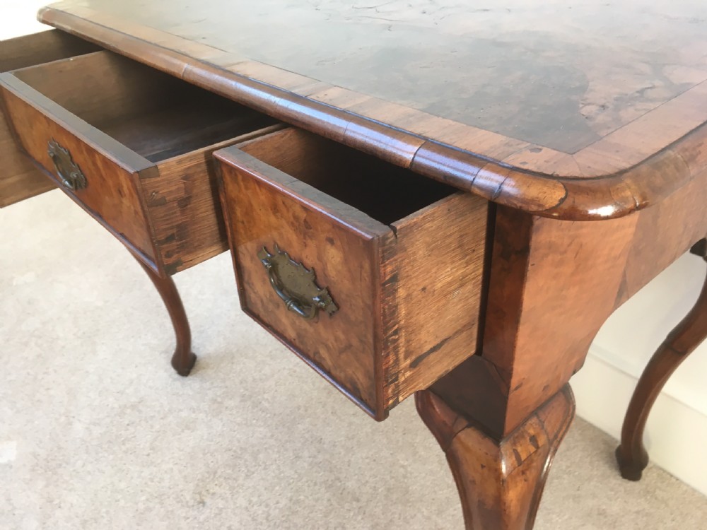 An eighteenth-century George II burr walnut lowboy featuring three drawers, brass handles, a shaped apron, and four slender cabriole legs. View X