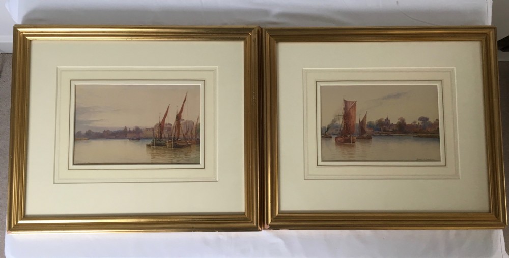 A pair of horizontally framed watercolour paintings depicting Thames sailing barges on calm water, enclosed in matching gilt frames with double mounts.