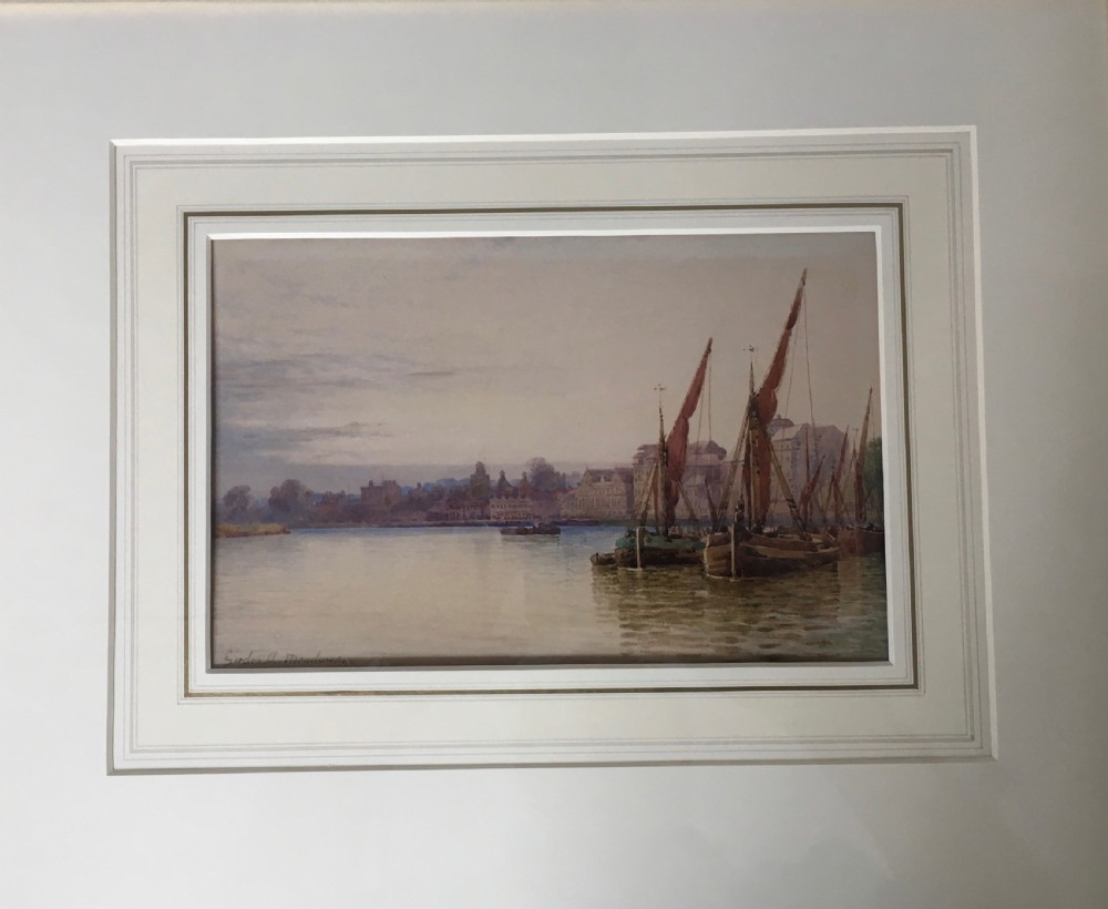 A pair of horizontally framed watercolour paintings depicting Thames sailing barges on calm water, enclosed in matching gilt frames with double mounts. View IV
