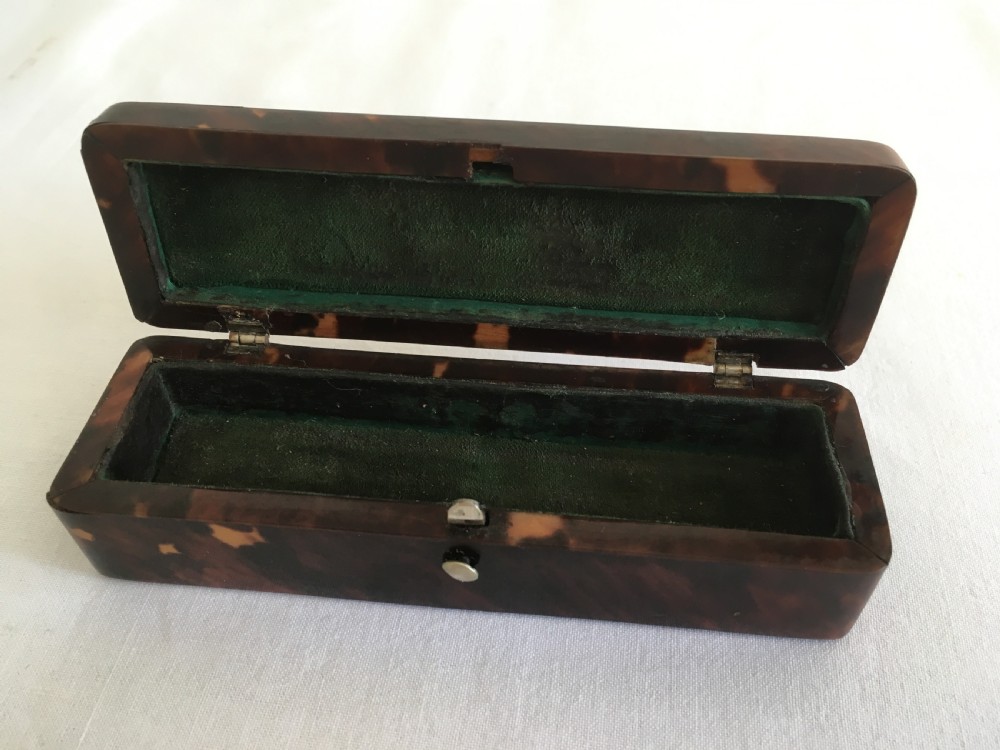 A rectangular mottled tortoiseshell box with rounded corners and an oval silver monogrammed plaque mounted on the lid. View III