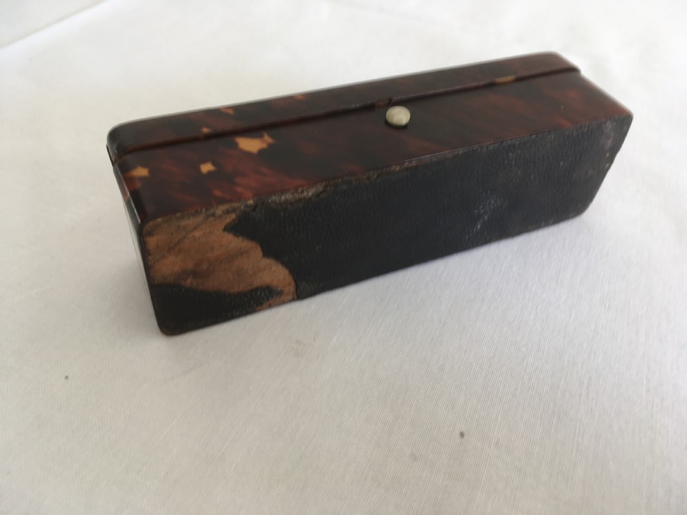 A rectangular mottled tortoiseshell box with rounded corners and an oval silver monogrammed plaque mounted on the lid. View VIII