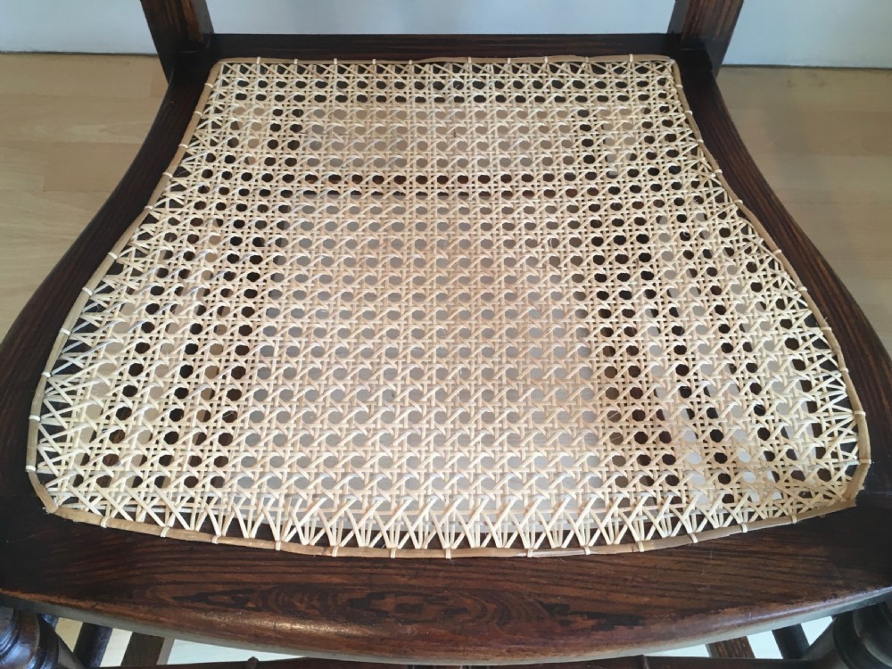 A dark wood 19th-century spindle back rocking chair featuring a woven cane seat, turned spindles, and curved armrests resting on curved runners. View VIII