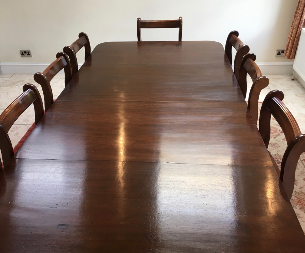 A 19th-century mahogany extendable dining table featuring a polished rectangular top with rounded corners, supported by two turned pillar pedestals on splayed legs with brass castors. View III