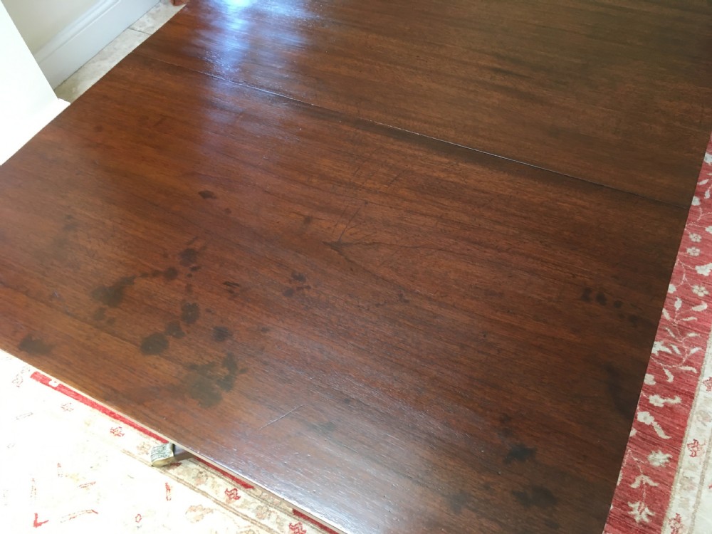 A 19th-century mahogany extendable dining table featuring a polished rectangular top with rounded corners, supported by two turned pillar pedestals on splayed legs with brass castors. View IX