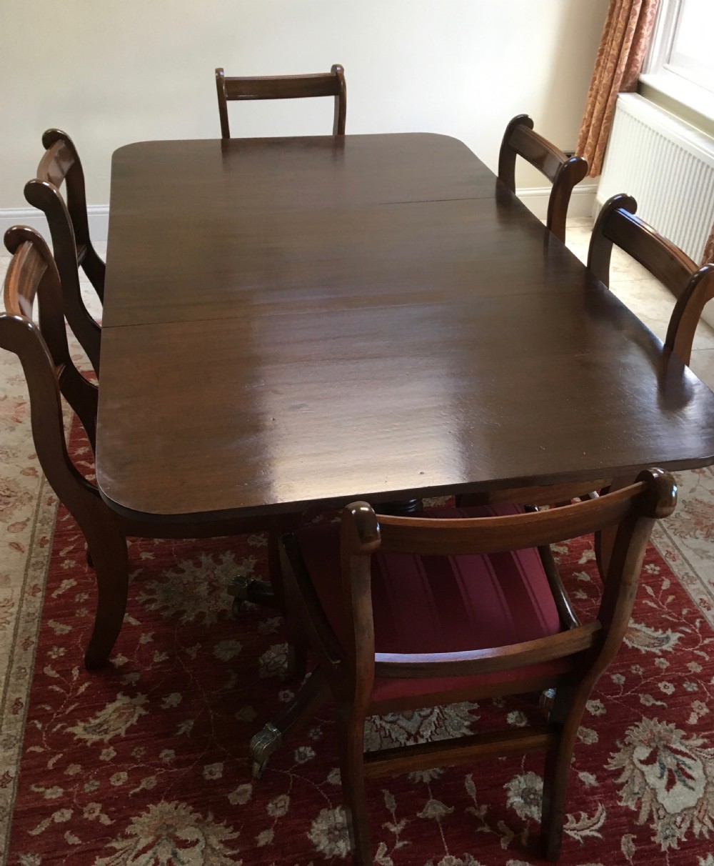 A 19th-century mahogany extendable dining table featuring a polished rectangular top with rounded corners, supported by two turned pillar pedestals on splayed legs with brass castors. View XII
