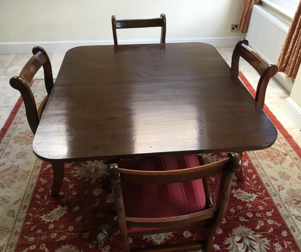 A 19th-century mahogany extendable dining table featuring a polished rectangular top with rounded corners, supported by two turned pillar pedestals on splayed legs with brass castors. View XIII