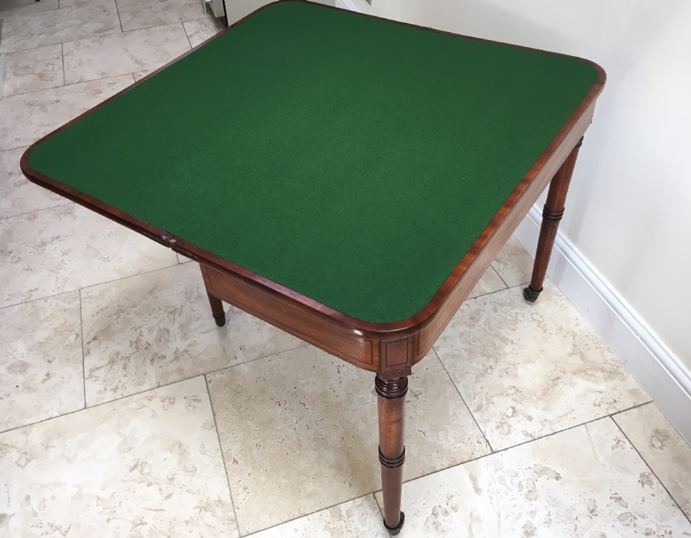 A Regency mahogany fold-over card table featuring turned tapered legs, brass castors, and boxwood stringing inlay along the frieze. View III