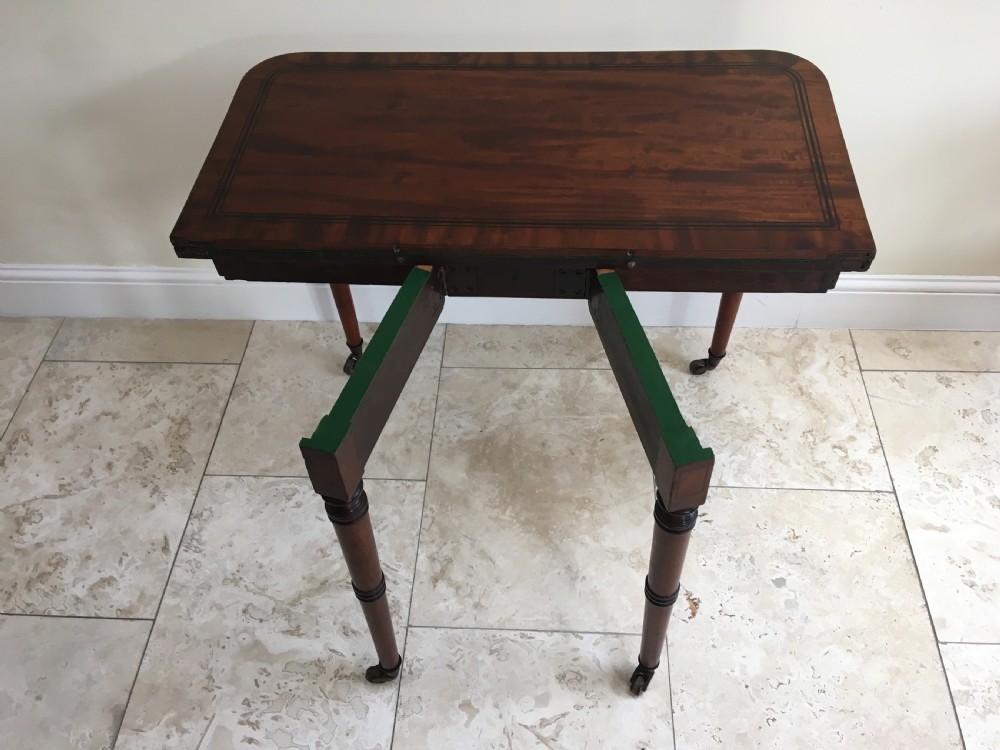 A Regency mahogany fold-over card table featuring turned tapered legs, brass castors, and boxwood stringing inlay along the frieze. View IV