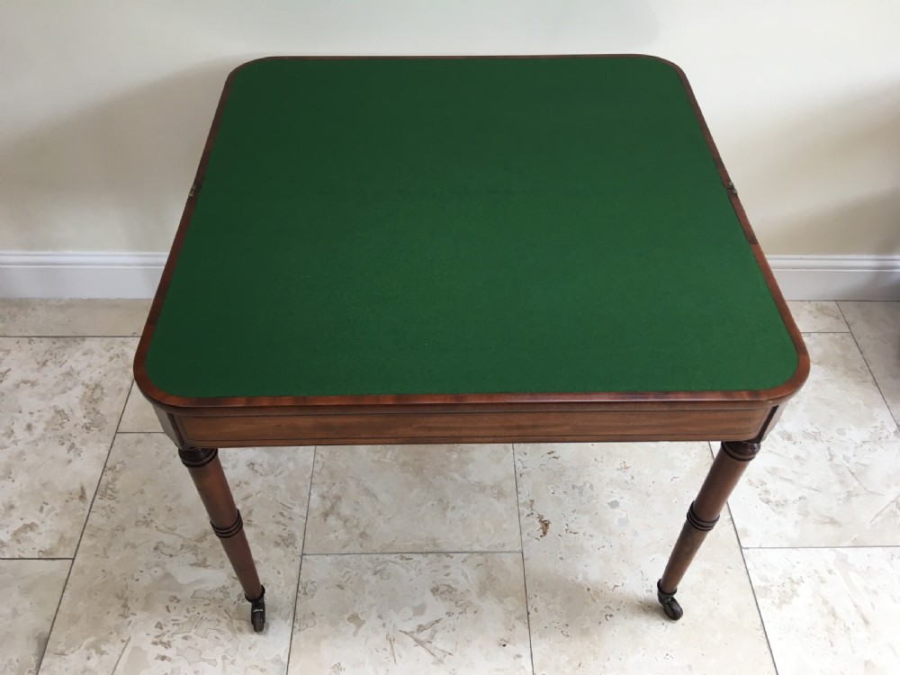 A Regency mahogany fold-over card table featuring turned tapered legs, brass castors, and boxwood stringing inlay along the frieze. View XII