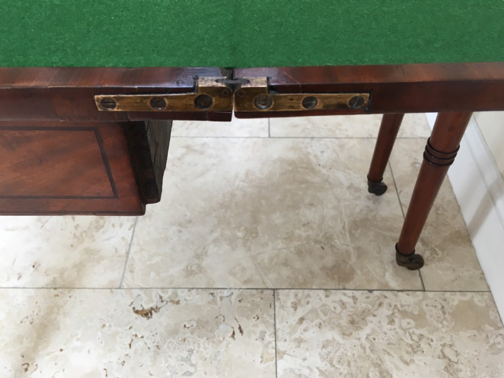 A Regency mahogany fold-over card table featuring turned tapered legs, brass castors, and boxwood stringing inlay along the frieze. View XIII
