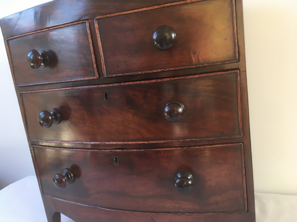 A miniature mahogany bow-fronted chest of drawers featuring turned wooden knobs and a polished grain finish. View XIII