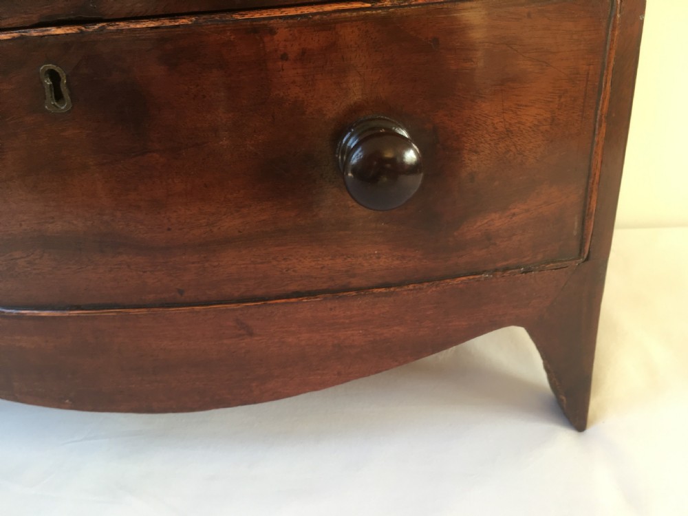 A miniature mahogany bow-fronted chest of drawers featuring turned wooden knobs and a polished grain finish. View XIV