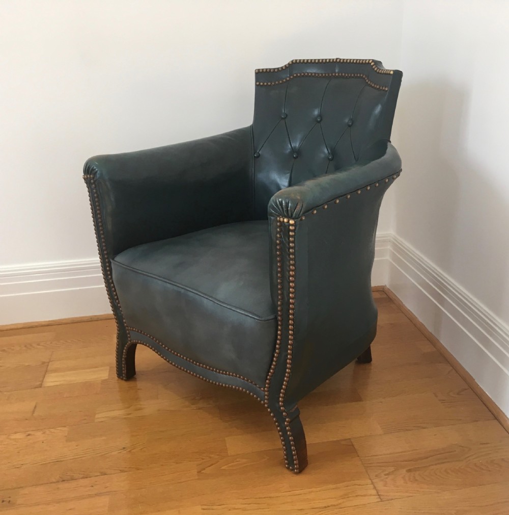 An Edwardian dark green leather library armchair featuring deep button tufting, brass stud trim, and dark timber legs. View II