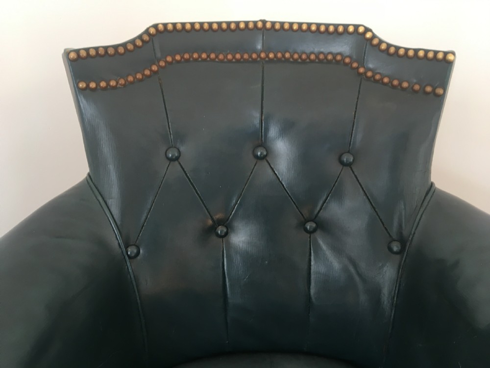 An Edwardian dark green leather library armchair featuring deep button tufting, brass stud trim, and dark timber legs. View III