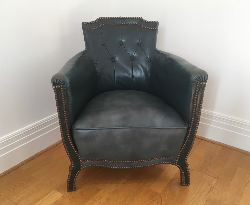 An Edwardian dark green leather library armchair featuring deep button tufting, brass stud trim, and dark timber legs. View IV
