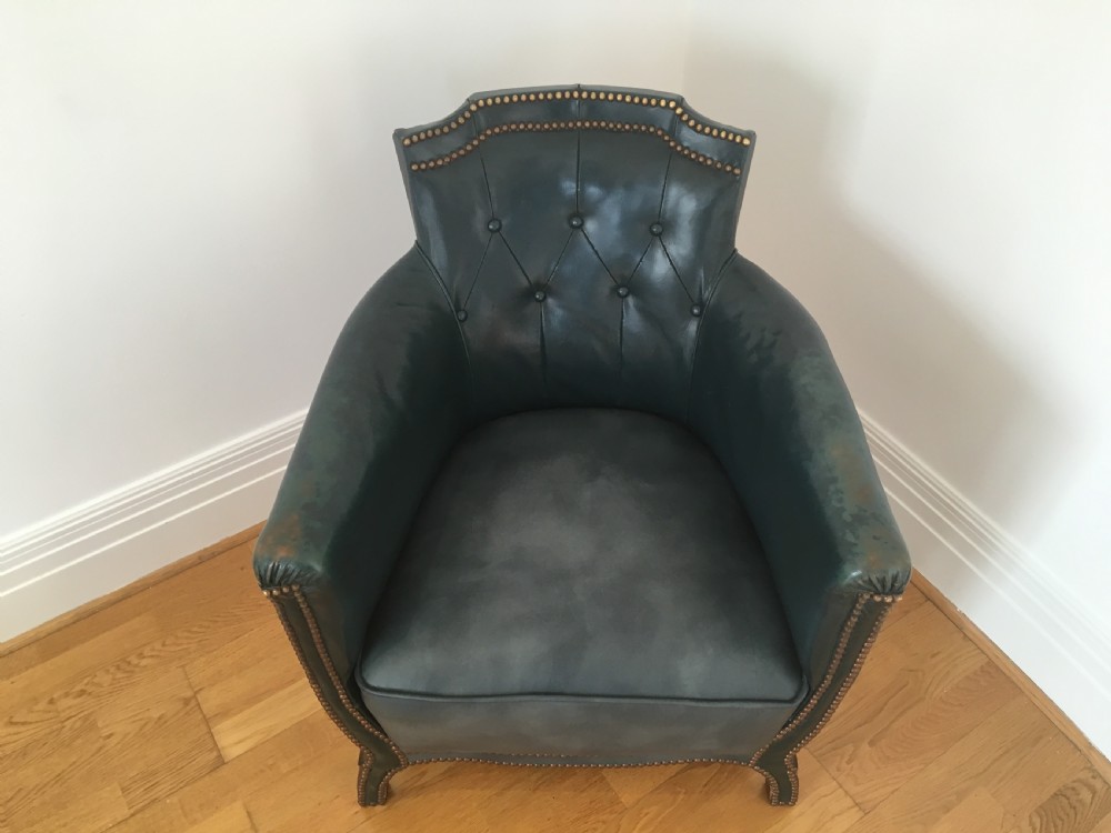 An Edwardian dark green leather library armchair featuring deep button tufting, brass stud trim, and dark timber legs. View VI