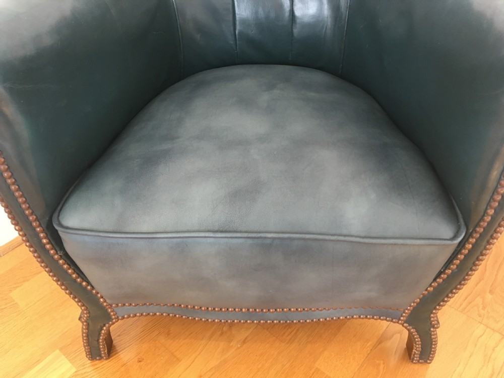 An Edwardian dark green leather library armchair featuring deep button tufting, brass stud trim, and dark timber legs. View VII