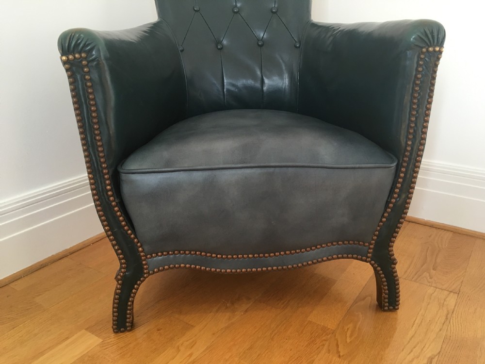 An Edwardian dark green leather library armchair featuring deep button tufting, brass stud trim, and dark timber legs. View VIII