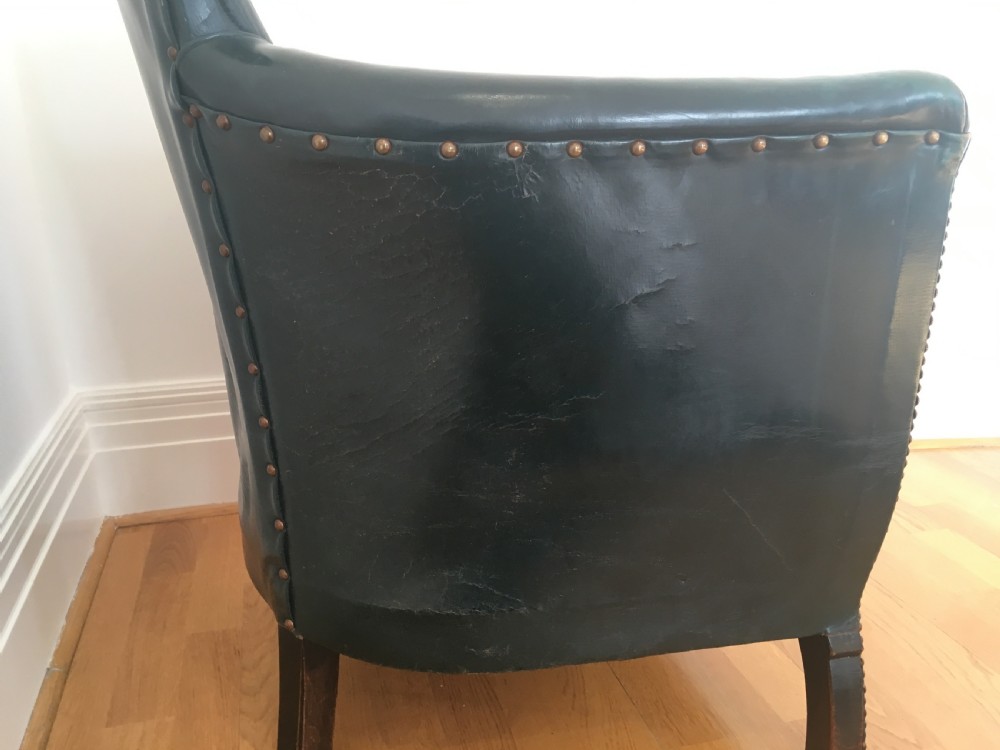 An Edwardian dark green leather library armchair featuring deep button tufting, brass stud trim, and dark timber legs. View XI