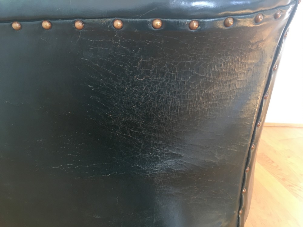 An Edwardian dark green leather library armchair featuring deep button tufting, brass stud trim, and dark timber legs. View XIV