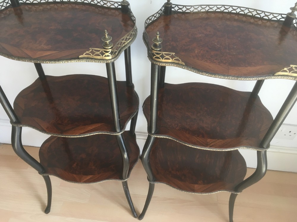 A pair of three-tiered French style side tables crafted from dark wood with inlaid marquetry work, gilt metal gallery rails, and cabriole legs. View V