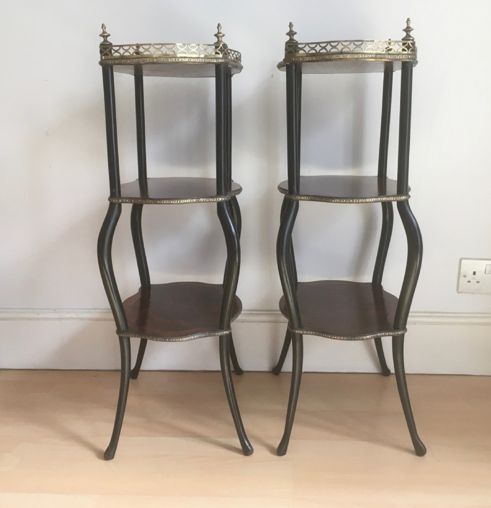 A pair of three-tiered French style side tables crafted from dark wood with inlaid marquetry work, gilt metal gallery rails, and cabriole legs. View VI