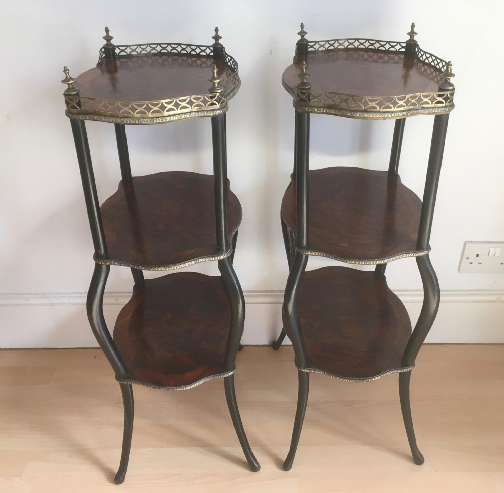 A pair of three-tiered French style side tables crafted from dark wood with inlaid marquetry work, gilt metal gallery rails, and cabriole legs. View VII
