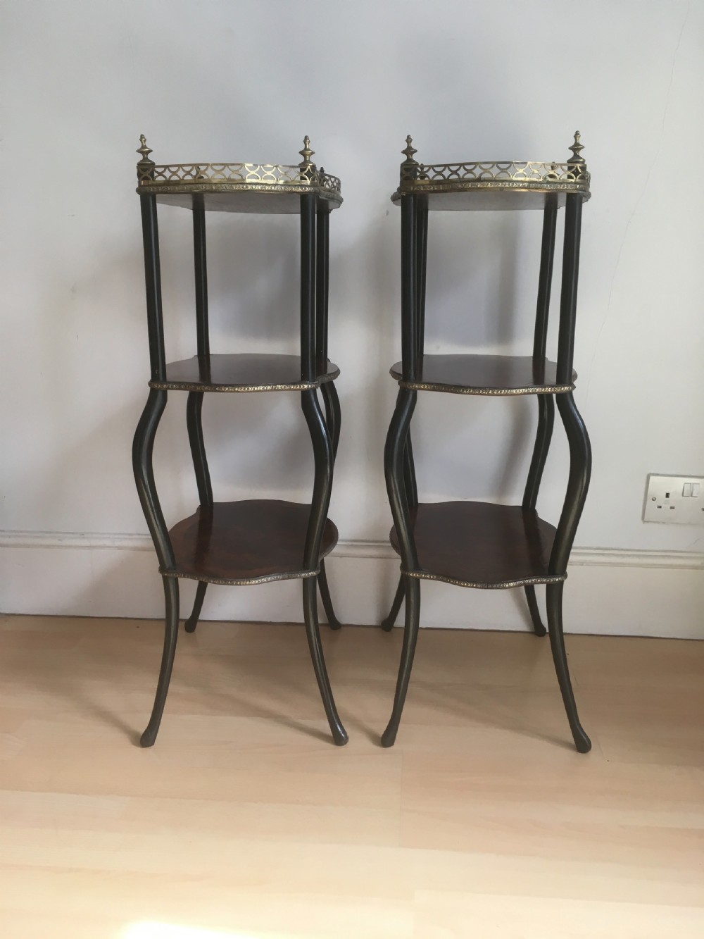 A pair of three-tiered French style side tables crafted from dark wood with inlaid marquetry work, gilt metal gallery rails, and cabriole legs. View VIII