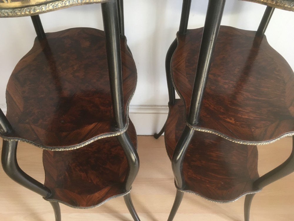 A pair of three-tiered French style side tables crafted from dark wood with inlaid marquetry work, gilt metal gallery rails, and cabriole legs. View X